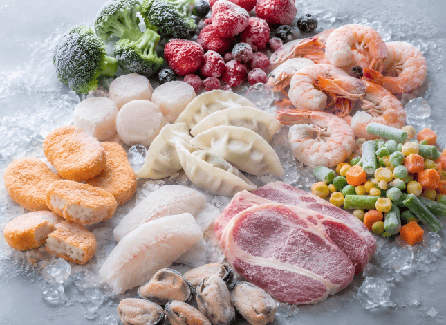Assorted frozen food including dumplings seafood meat vegetables and fruit on ice for frozen food packaging applications