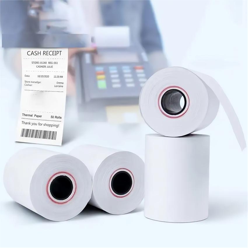 Thermal receipt paper rolls beside a POS terminal printing a customer receipt