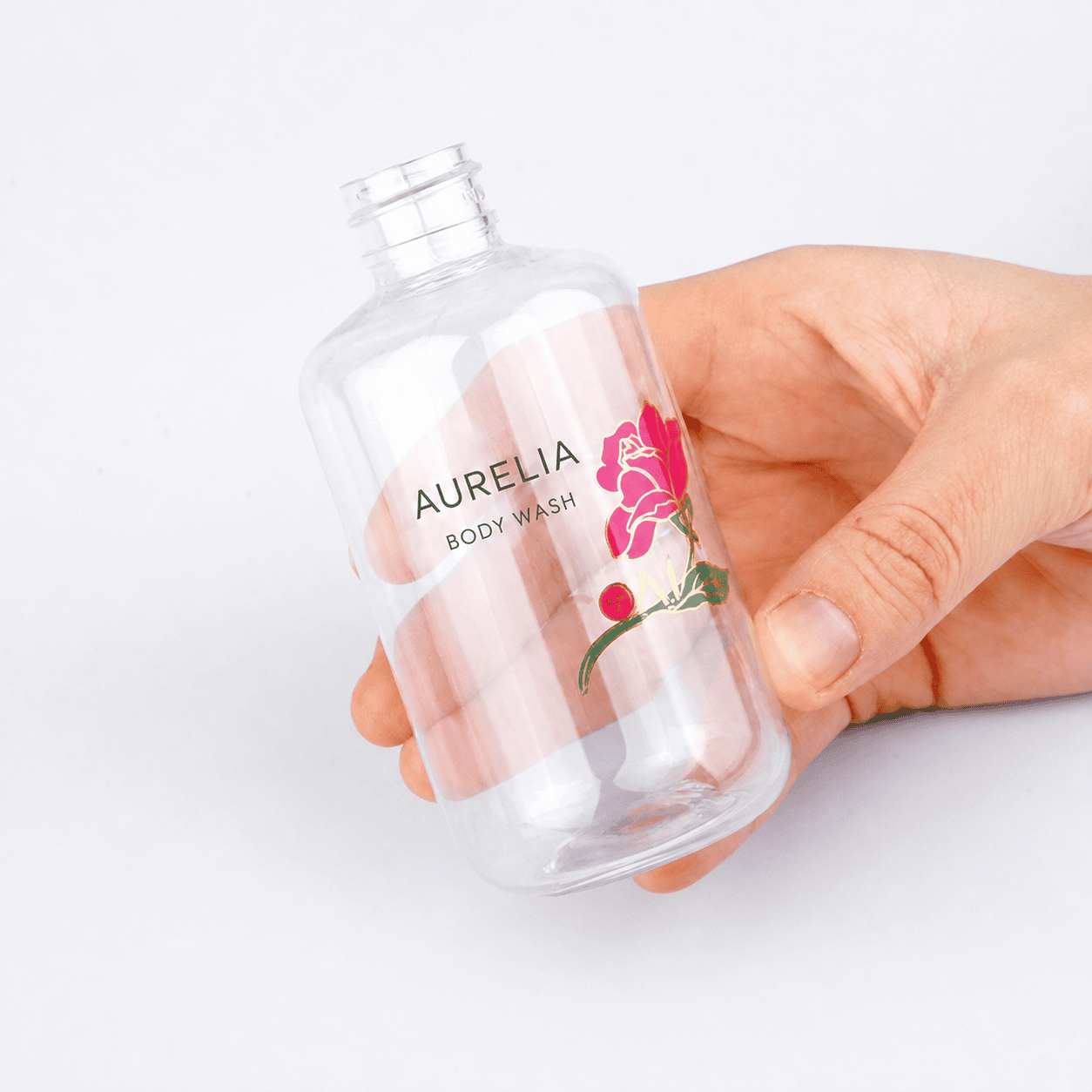 Clear cosmetic label applied to a transparent bottle held by hand
