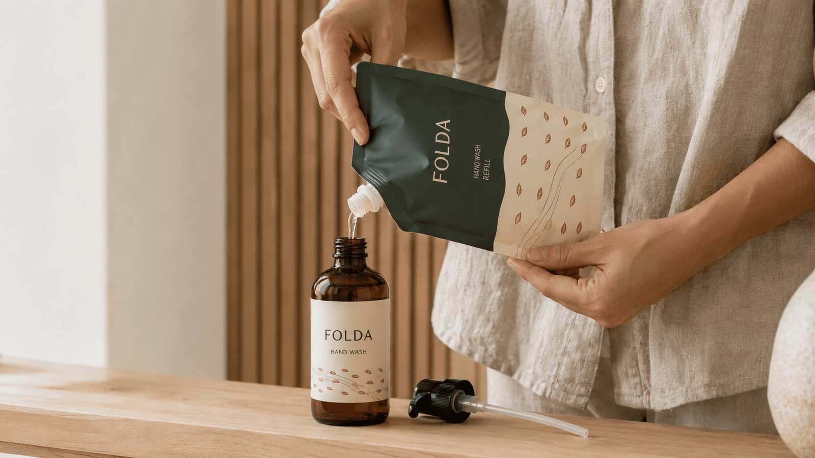 Hand refilling an amber hand wash bottle from a spout pouch