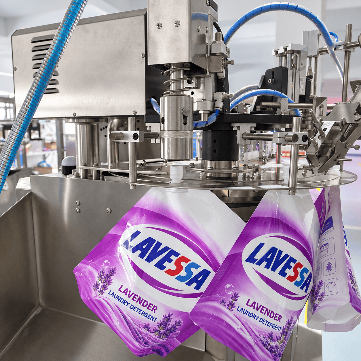 Laundry detergent spout pouches positioned beneath a rotary capping head