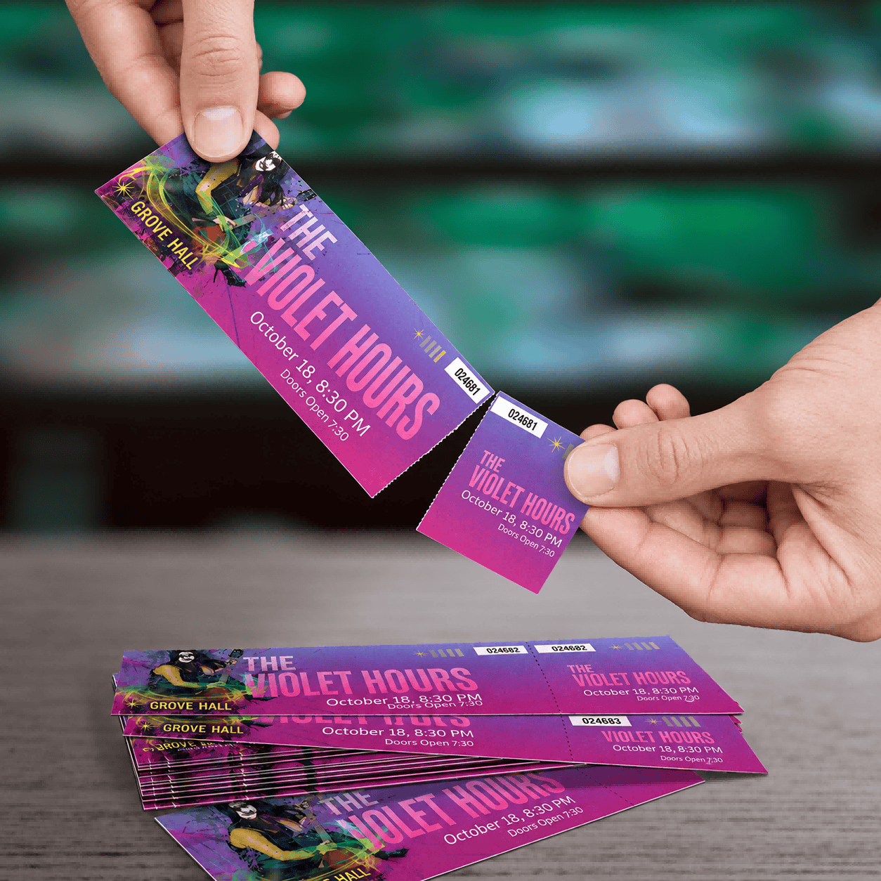 Hands separating a purple event ticket from its stub, with matching numbers on both parts