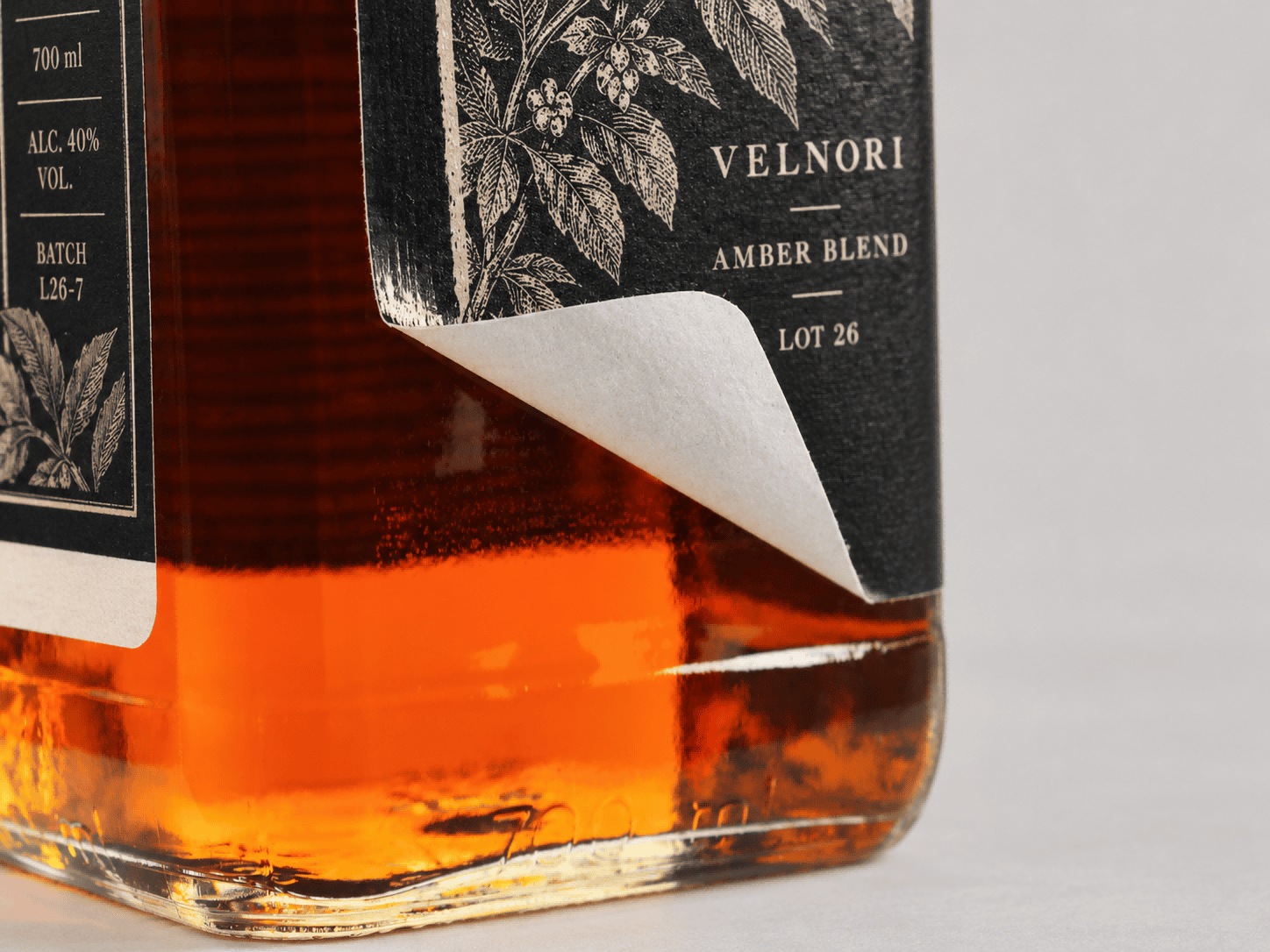 Black paper label curling away from the lower corner of an amber glass bottle