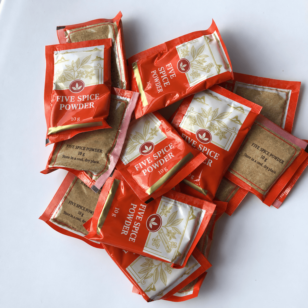Red printed five-spice powder sachets showing front panels and transparent back panels containing the powder