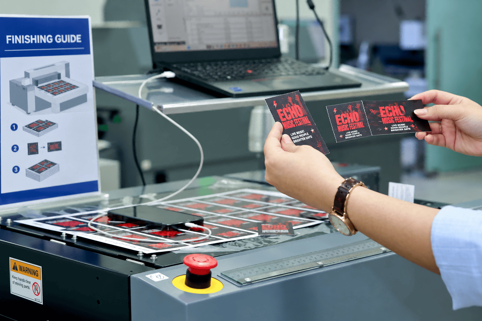 Hands checking a strip of printed event tickets beside finishing equipment